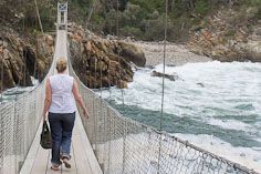 The final section of a three-span pedestrian suspension bridge stretches across the mouth of the Storms River.