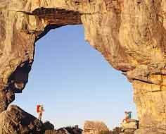 Two hikers enjoy their surrounds below the Wolfberg Arch, which is located in the Cederberg Wilderness Reserve, within the Cederberg Mountains.