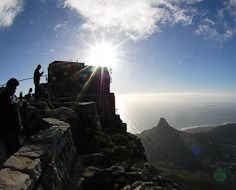 Visitors take in the view from atop Table Mountain as the sun sets over Lions Head and Cape Town below.